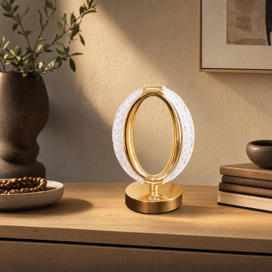 Oval crystal and brass rechargeable lamp on a pale oak console