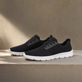 Lightweight sneakers in black on a sand-toned plinth