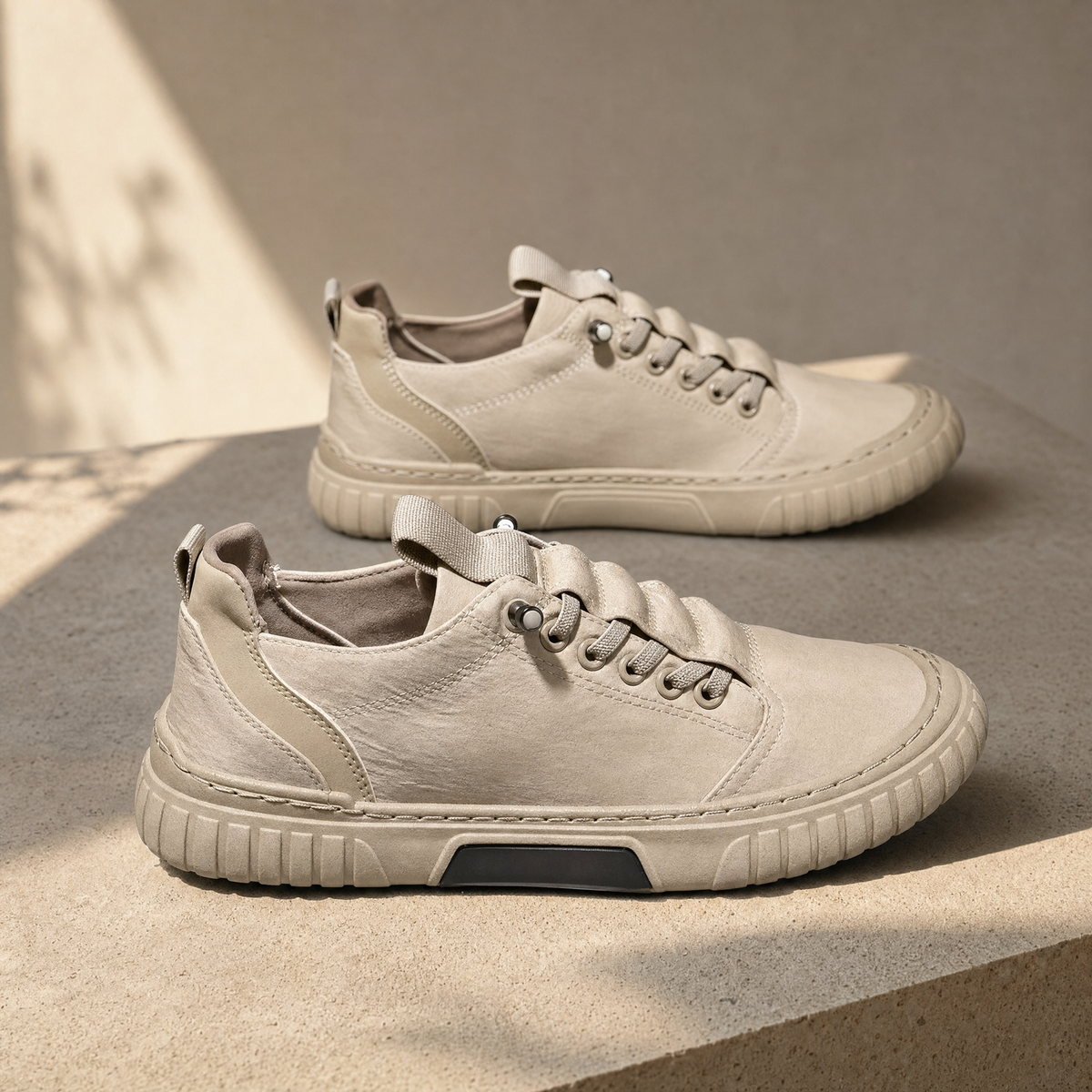Men's casual shoes in cream on a sand-toned plinth
