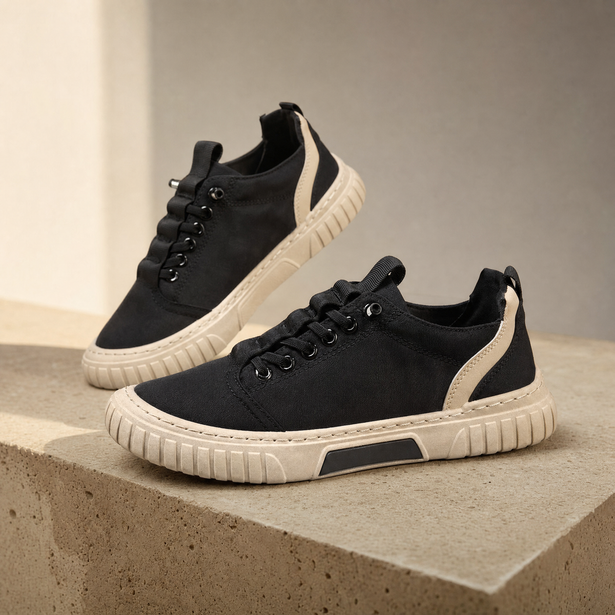 Men's casual shoes in black on a sand-toned plinth